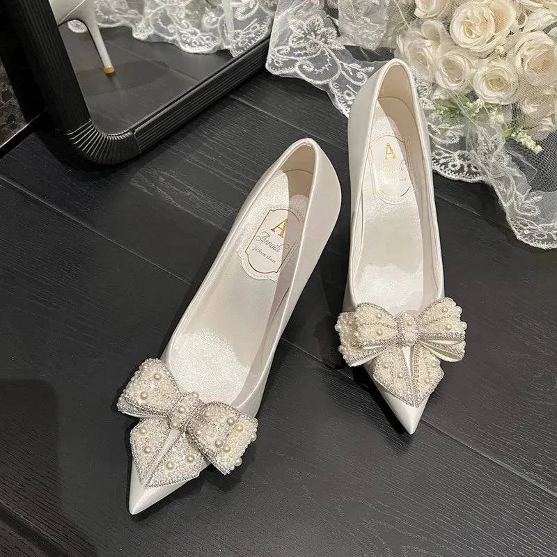 White satin stiletto wedding shoes with pointed toe, pearl bow detail, by LYNHURD for brides.