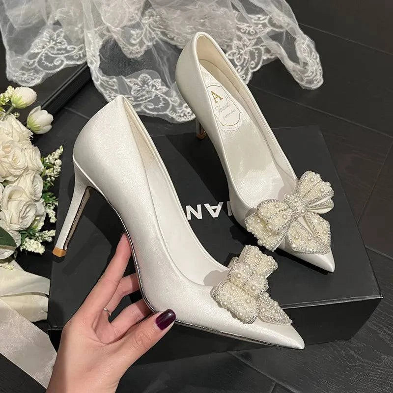White satin stiletto wedding shoes with pointed toe, pearl bow detail by LYNHURD for women.