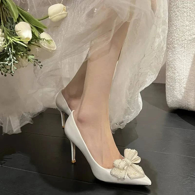 White satin stiletto wedding shoes with pointed toe, pearl bow detail by LYNHURD! for brides.